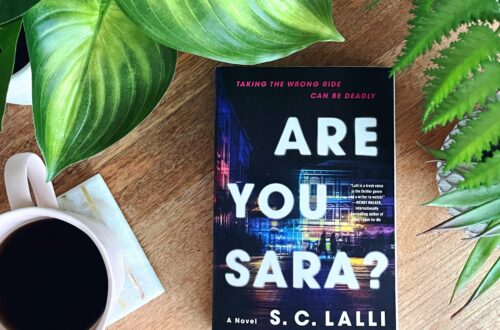 The photo shows the cover of Are You Sara? A debut psychological thriller by S.C. Lallil. The cover is predominently black with glimpes of a colorful city street.